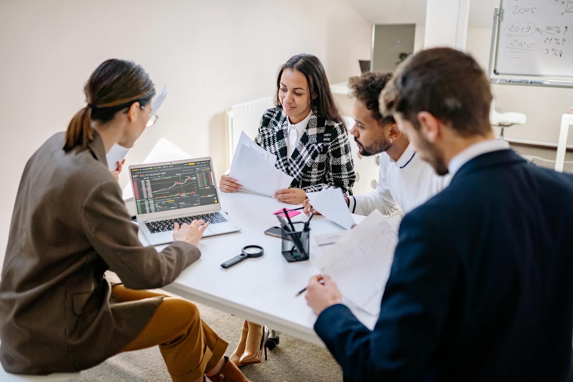 A team discussing financial reports on a tablet in a meeting room.